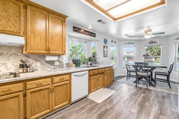a kitchen with stainless steel appliances granite countertop wooden cabinets a dining table and chairs
