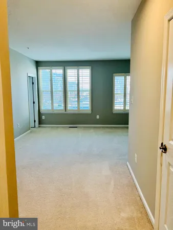 a view of a hallway to a room with cabinet and mirror
