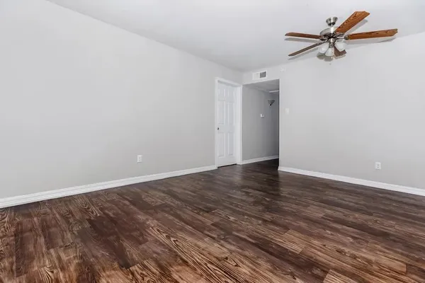 a view of a room with wooden floor and a ceiling fan