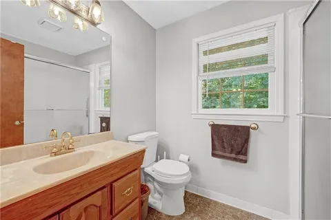 a bathroom with a toilet a sink a mirror and a window