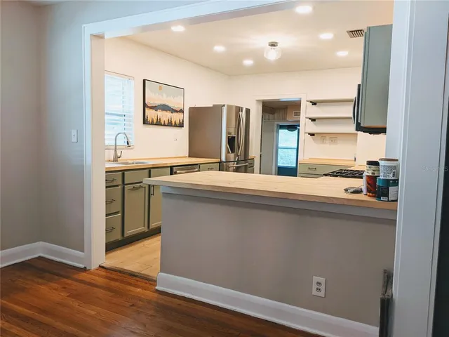 a kitchen with stainless steel appliances granite countertop a sink a stove a refrigerator and island with wooden floor