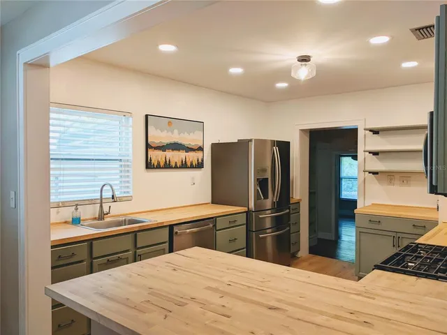 a kitchen with stainless steel appliances kitchen island granite countertop a refrigerator and a sink
