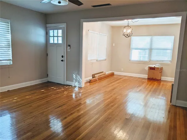 an empty room with wooden floor and windows