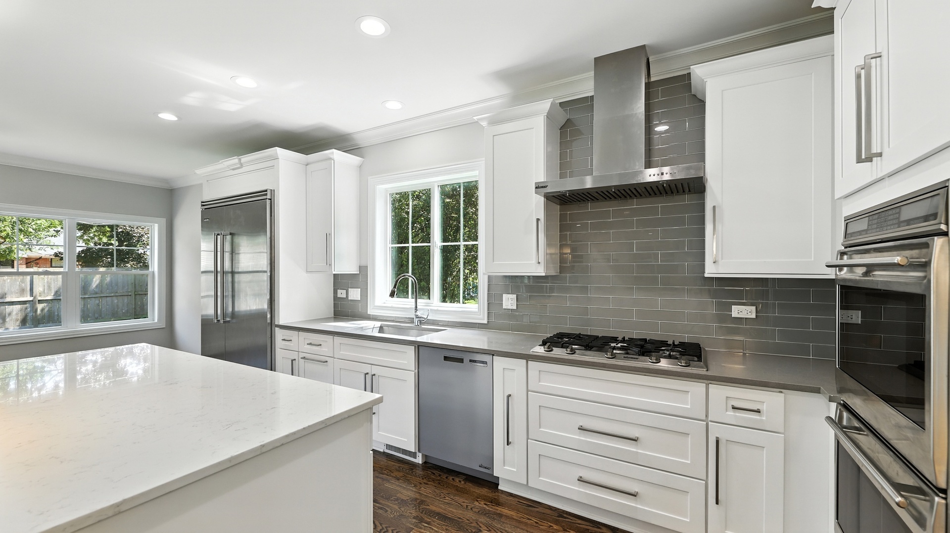 1127 Kenton Road Deerfield, IL 60015 - Photo 8 of 32 a kitchen with granite countertop a stove a sink dishwasher and white cabinets with wooden floor