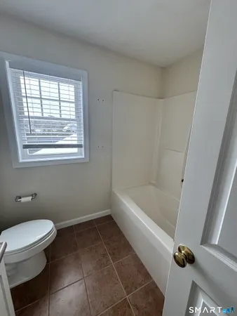 a bathroom with a tub a toilet and a window