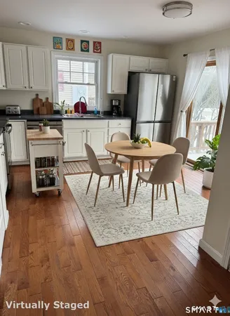 a living room with furniture a rug a kitchen appliances and a dining table view