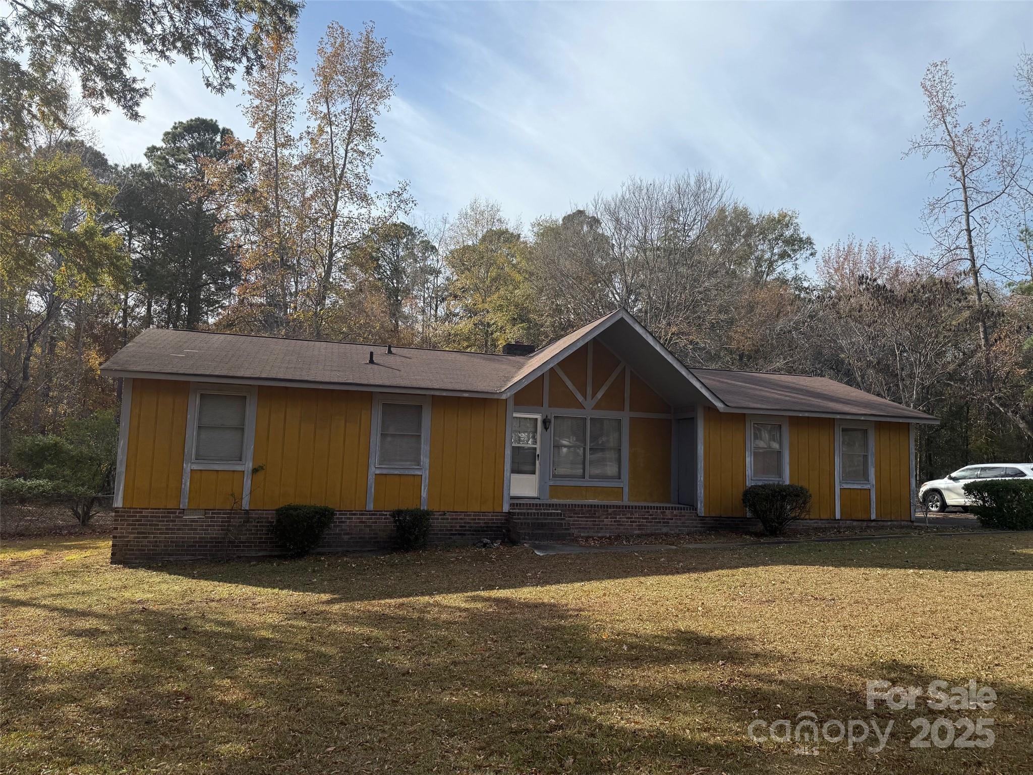 a front view of a house with a garden and trees