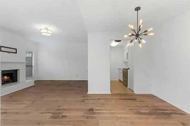 a view of an empty room with chandelier fan and fireplace