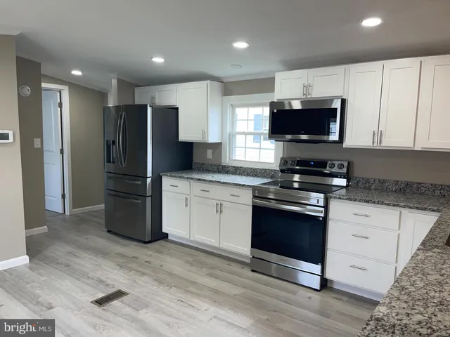 a kitchen with stainless steel appliances granite countertop a refrigerator stove a sink and a microwave