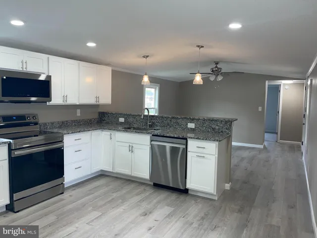 a kitchen with stainless steel appliances granite countertop a stove a sink and a microwave