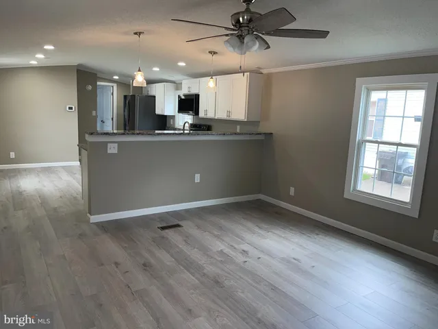 an open kitchen with kitchen island white cabinetry and stainless steel appliances