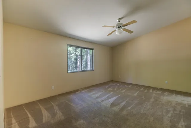 an empty room with a window and a fan