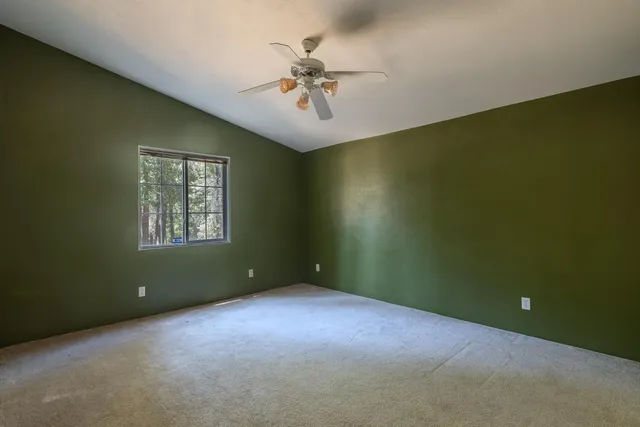 an empty room that has a window and a ceiling fan