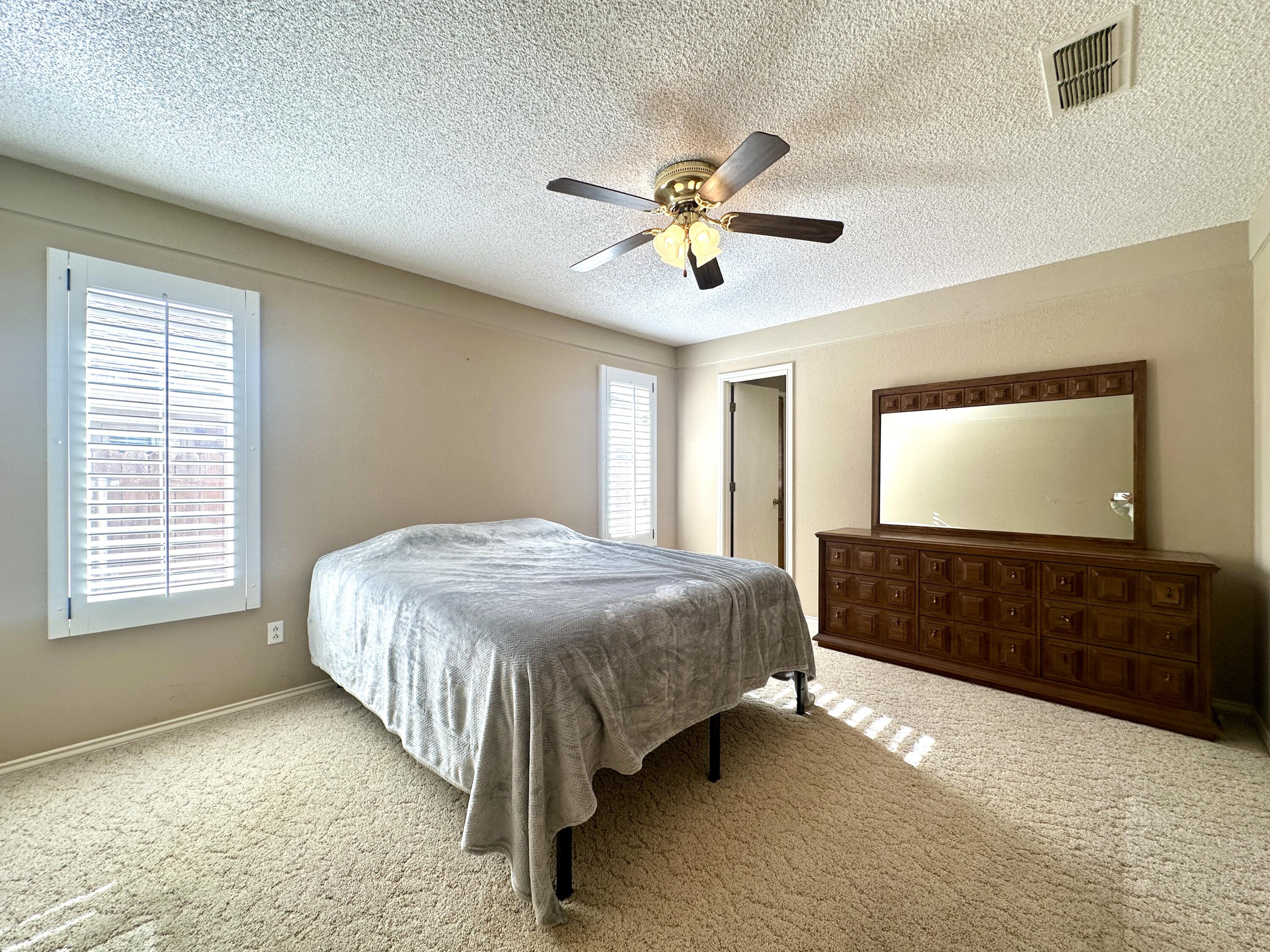 8614 Memphis Avenue, Unit B Lubbock, TX 79423 - Photo 8 of 11 a spacious bedroom with a bed and a chandelier