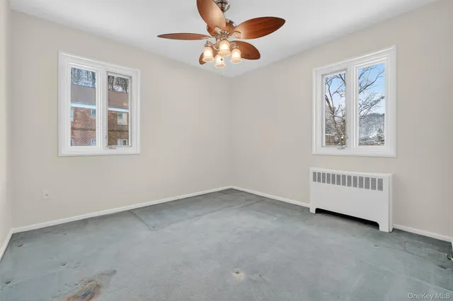 an empty room with windows and fan