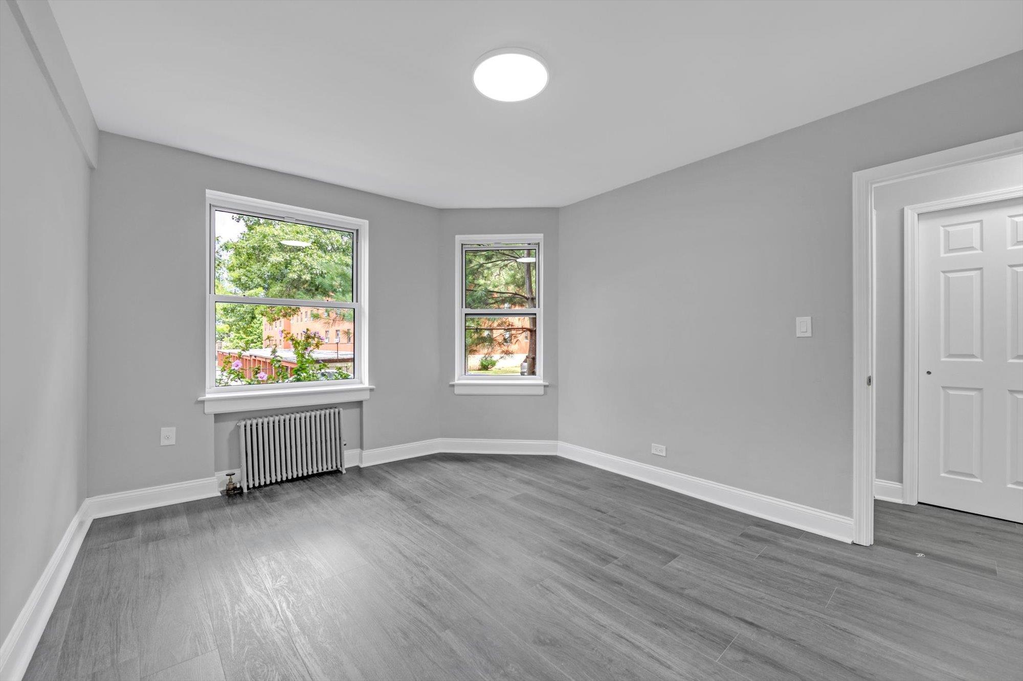 141-24 78th Avenue, Unit 1A Queens, NY 11367 - Photo 11 of 12 an empty room with wooden floor and windows