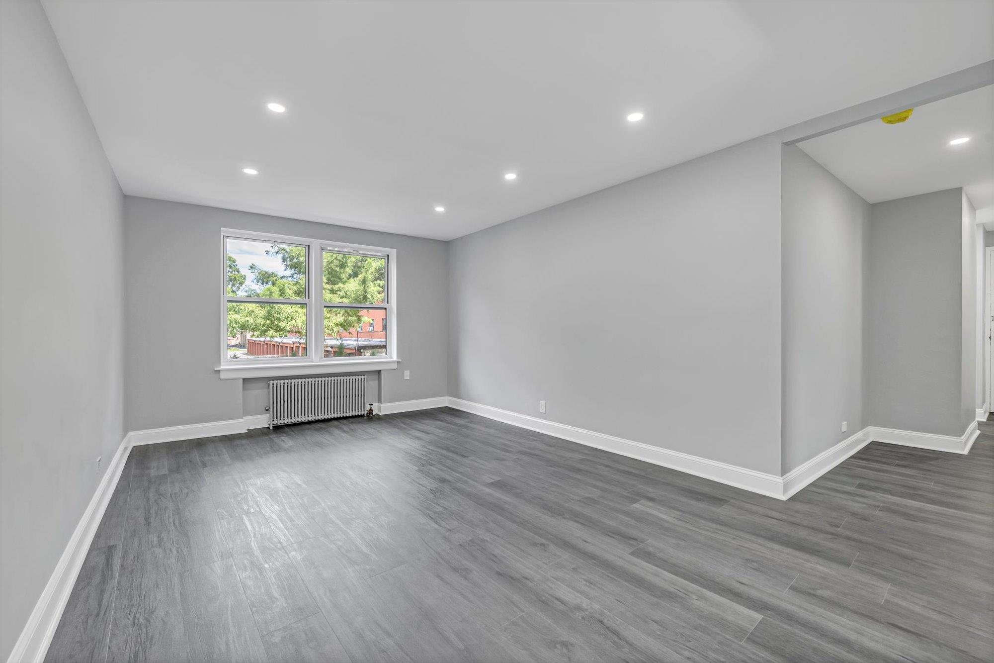 141-24 78th Avenue, Unit 1A Queens, NY 11367 - Photo 3 of 12 a view of an empty room with wooden floor and a window