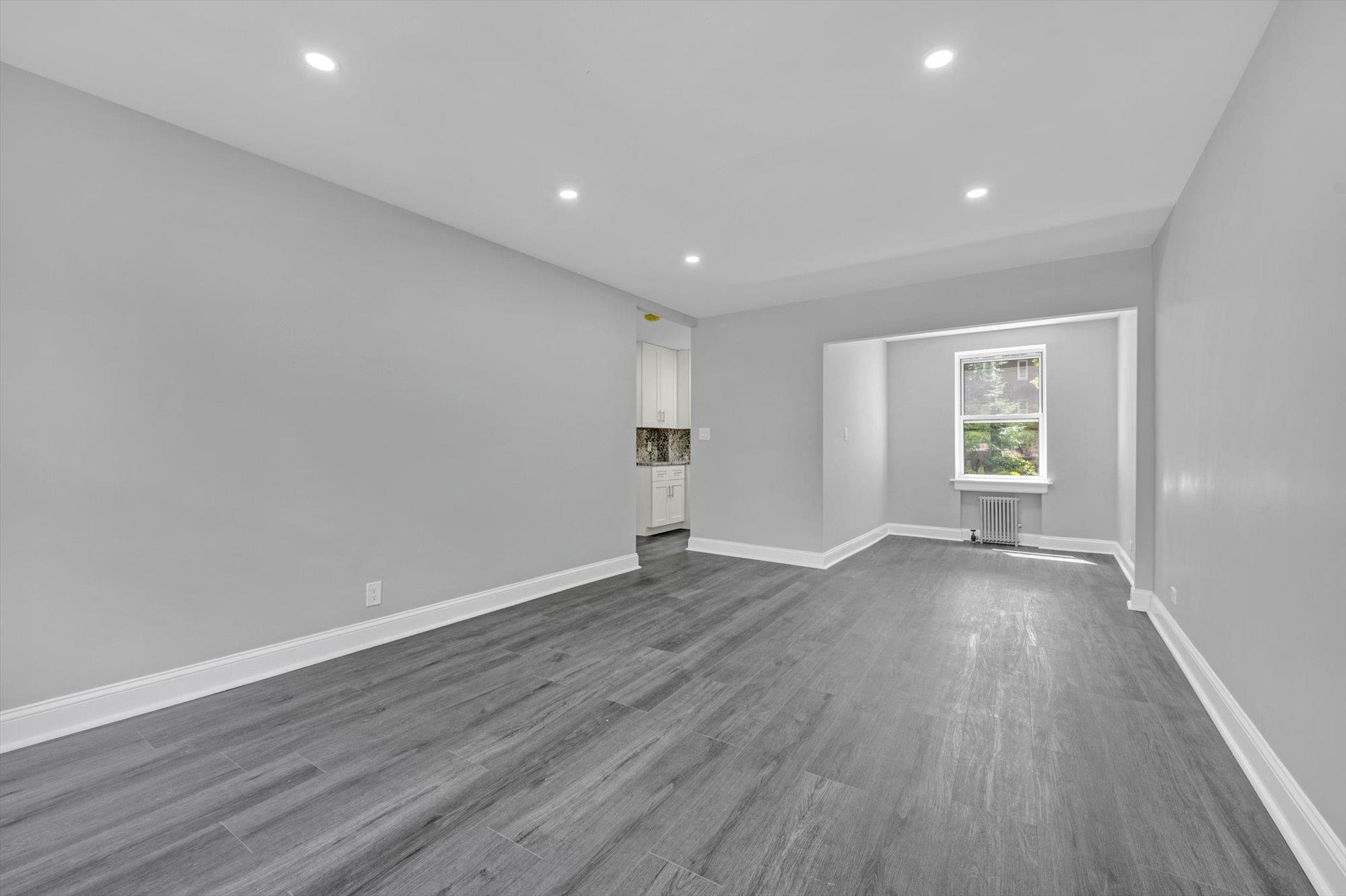 141-24 78th Avenue, Unit 1A Queens, NY 11367 - Photo 4 of 12 an empty room with wooden floor and windows