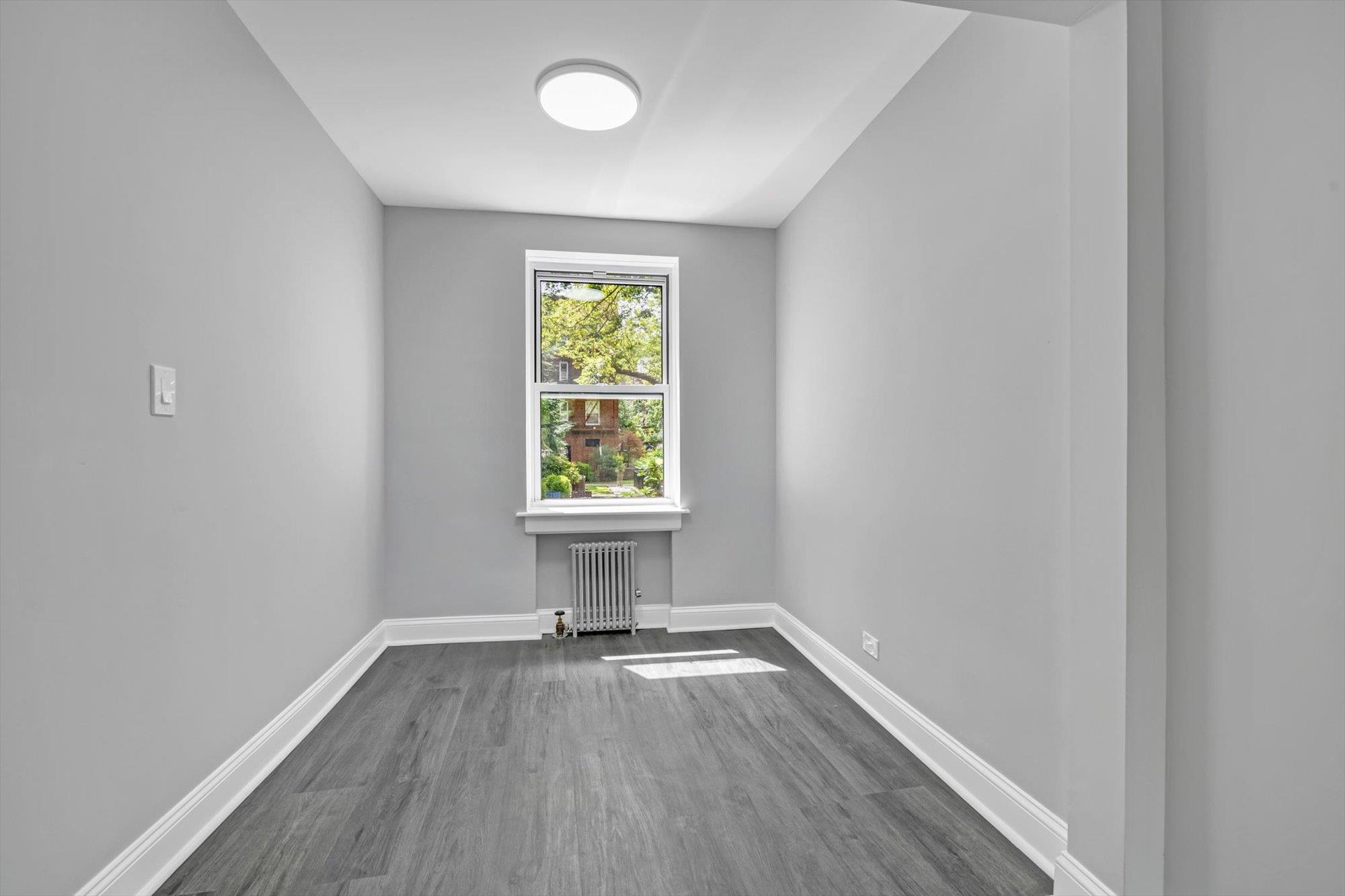 141-24 78th Avenue, Unit 1A Queens, NY 11367 - Photo 5 of 12 an empty room with wooden floor and windows