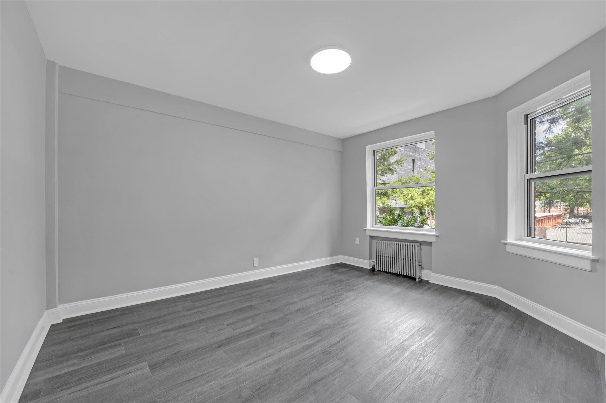 141-24 78th Avenue, Unit 1A Queens, NY 11367 - Photo 10 of 12 an empty room with wooden floor and windows