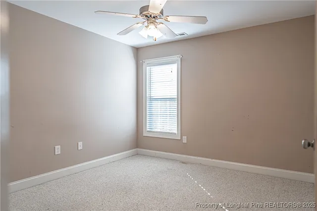 an empty room with a chandelier fan and windows