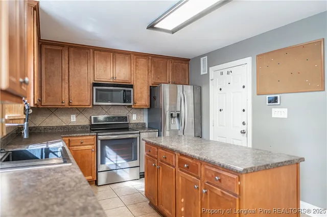 a kitchen with granite countertop stainless steel appliances a refrigerator cabinets and wooden floor