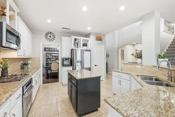 a large kitchen with stainless steel appliances granite countertop a lot of counter space and refrigerator