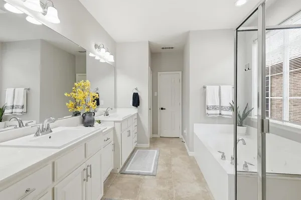 a bathroom with a double vanity sink and mirror with bathtub