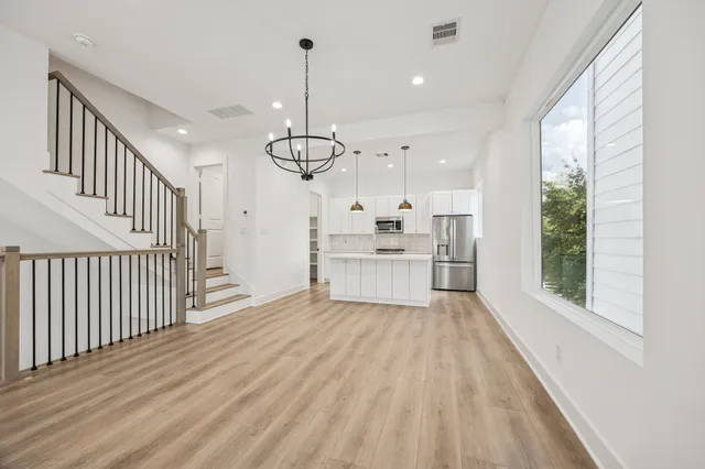 a view of kitchen with stainless steel appliances granite countertop a stove top oven a sink with wooden floor and cabinets