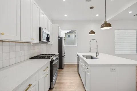 a kitchen with stainless steel appliances a sink a stove and a wooden floors