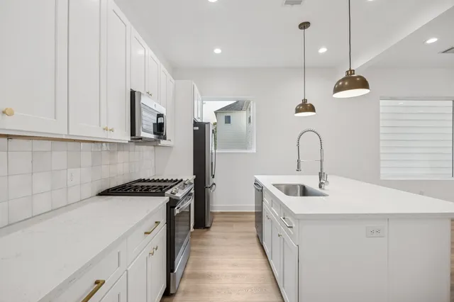 a kitchen with stainless steel appliances a sink a stove and a wooden floors