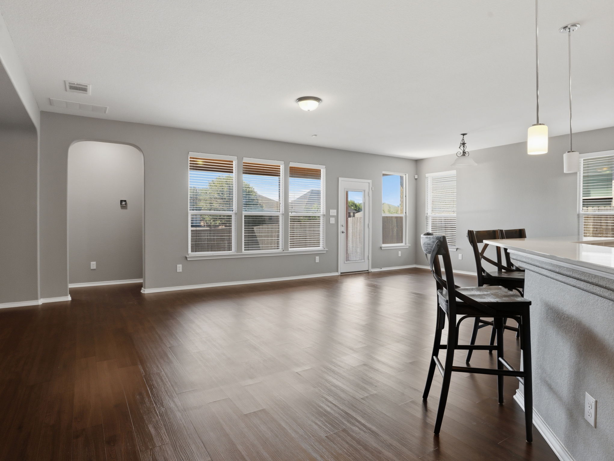 640 Landon Samuel Loop Pflugerville, TX 78660 - Photo 5 of 33 Expansive open-concept living area featuring wood-finish flooring, abundant natural light from multiple windows, an arched doorway, and recessed lighting