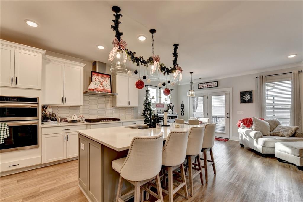 572 Redfish Way Hoschton, GA 30548 - Photo 13 of 67 a kitchen with kitchen island granite countertop a sink and white cabinets