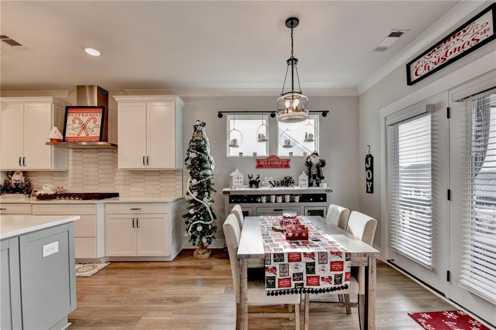 572 Redfish Way Hoschton, GA 30548 - Photo 20 of 67 a kitchen with stainless steel appliances kitchen island granite countertop a table and chairs in it