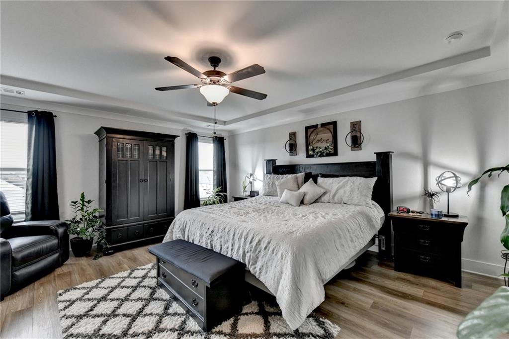 572 Redfish Way Hoschton, GA 30548 - Photo 28 of 67 a bedroom with a large bed and a chandelier