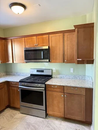 a kitchen with stainless steel appliances granite countertop wooden cabinets a stove and a sink