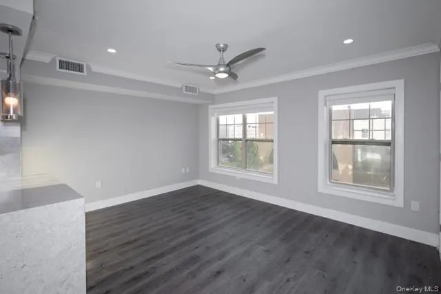 an empty room with wooden floor ceiling fan and windows