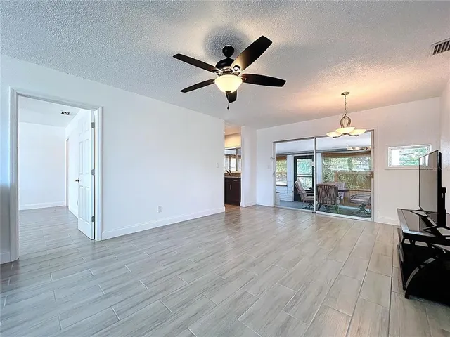 a view of a livingroom with wooden floor a ceiling fan and a window