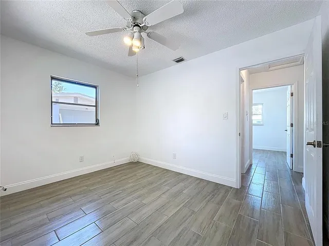 a view of room with window ceiling fan and hardwood floor