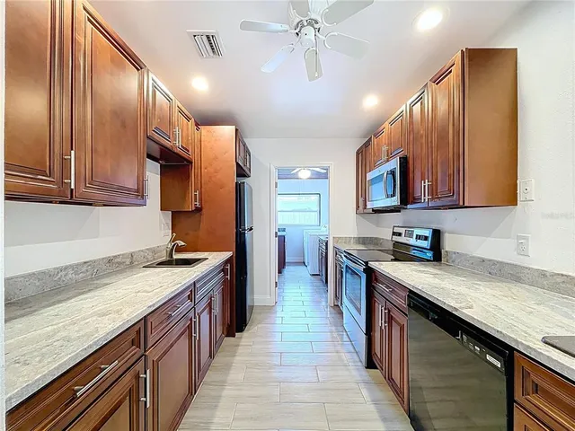 a kitchen with stainless steel appliances granite countertop a sink a stove top oven a refrigerator cabinets and wooden floor