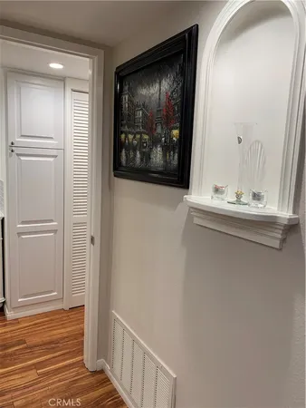 a view of a hallway with wooden floor and cabinet