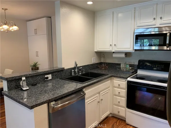 a kitchen with granite countertop a sink a stove and cabinets