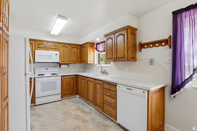 2348 North 770 West Clinton, UT 84015 - Photo 6 of 25 U-shaped kitchen featuring wood cabinetry, white countertops, a white oven/range, a built-in microwave, and a white dishwasher
