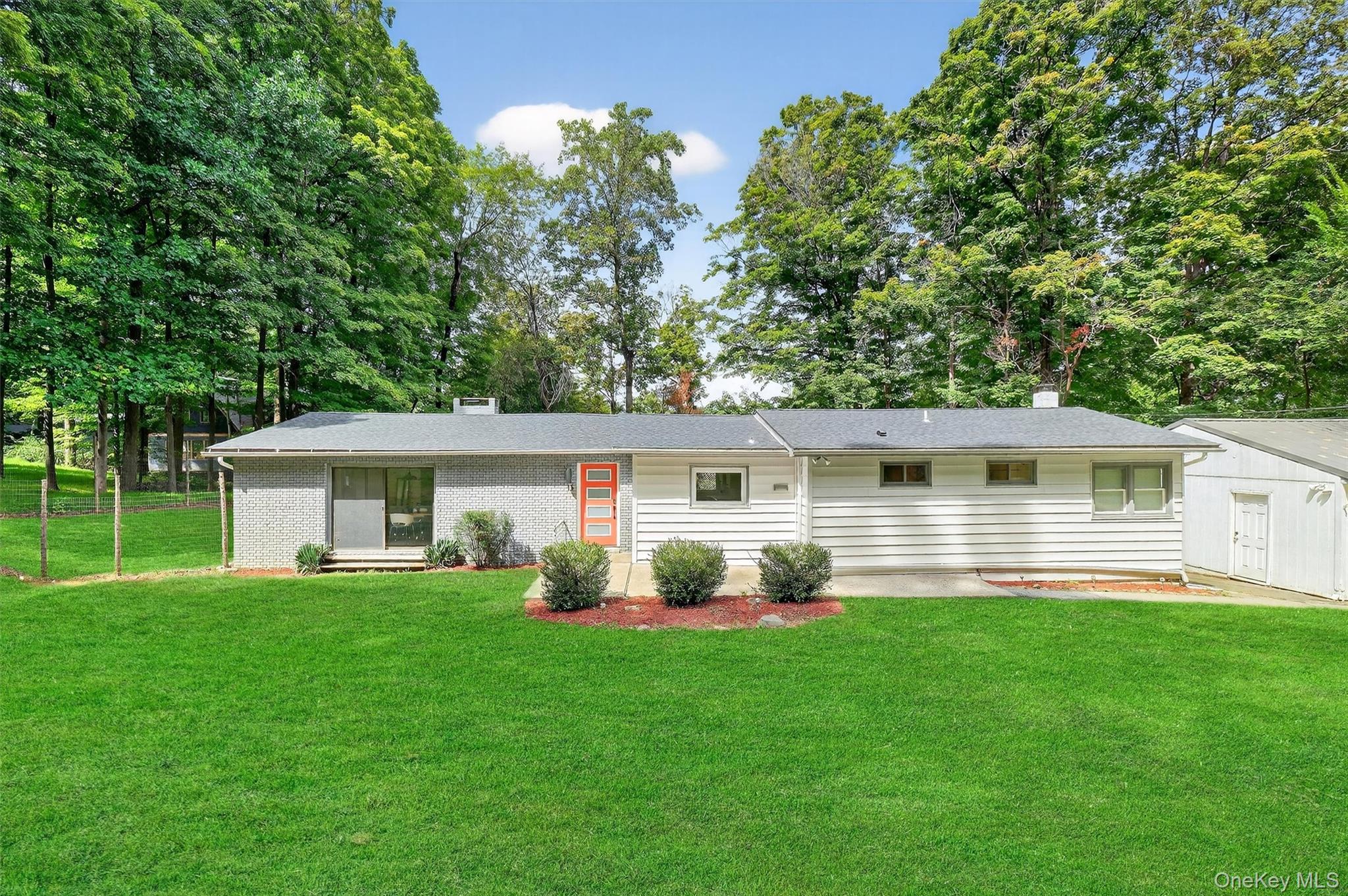 Ranch-style home featuring brick siding, a front lawn, an attached garage, and roof with shingles