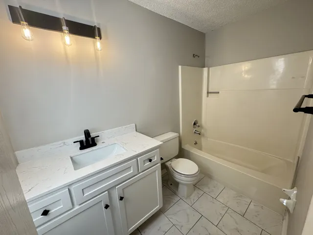 a view of an empty room with wooden floor and cabinets