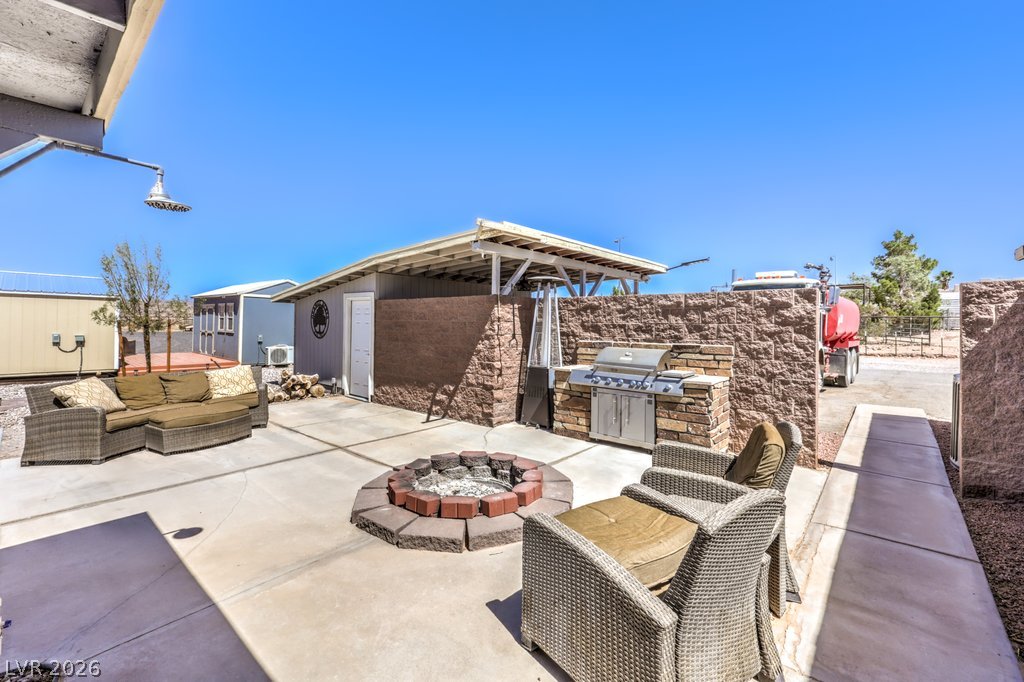 4375 Pinwheel Street Logandale, NV 89021 - Photo 33 of 52 An inviting backyard patio features a fire pit, built-in barbecue, and comfortable seating.