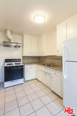 a kitchen with granite countertop a cabinets and a stove top oven