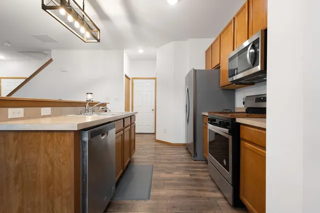 a kitchen with stainless steel appliances granite countertop a refrigerator a stove and a sink with wooden floor