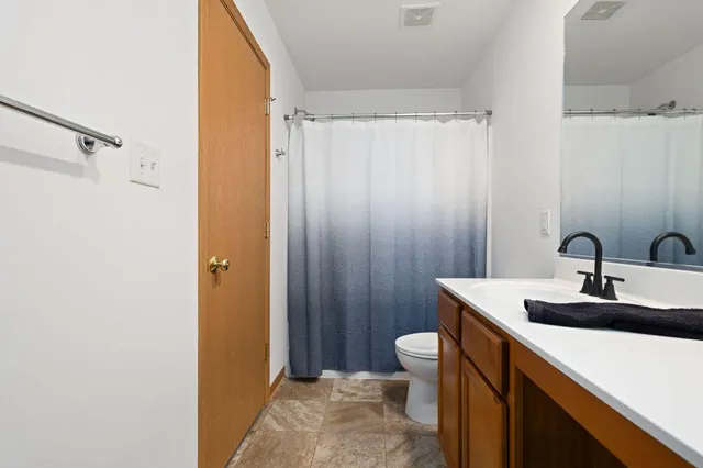 a bathroom with a sink a toilet a mirror and shower curtain