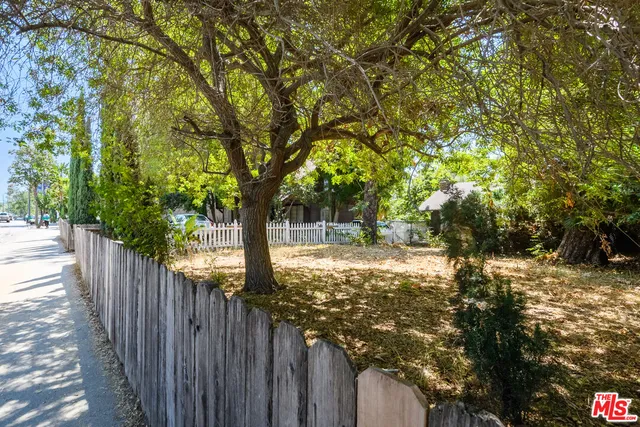 a view of a yard with wooden fence and trees